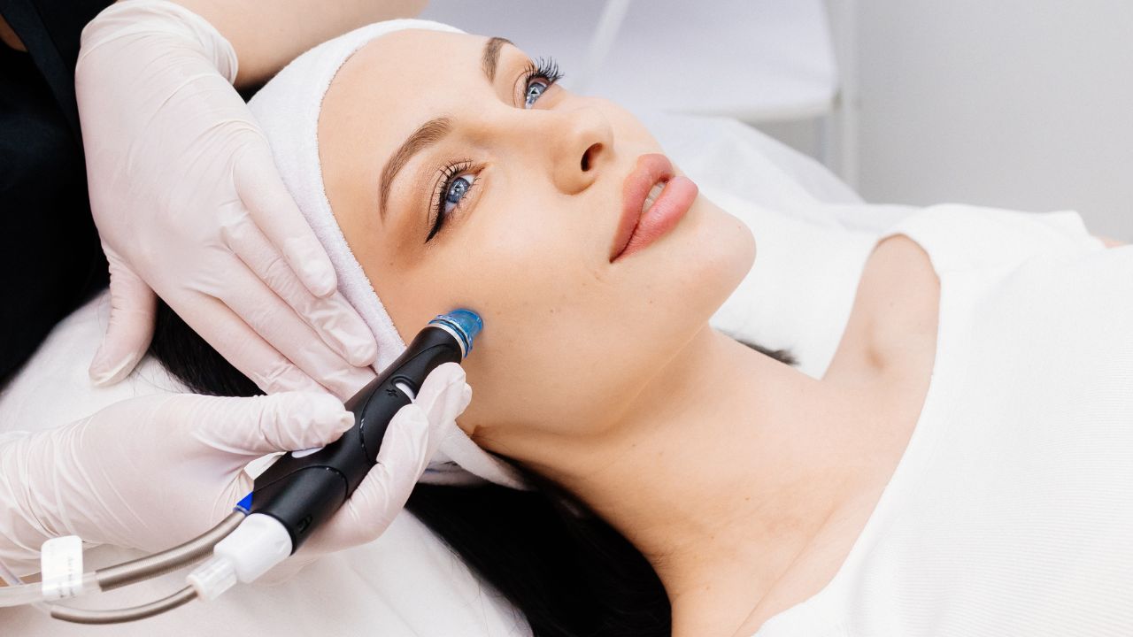 female cosmetologist performs a hydrafacial treatment on an attractive woman